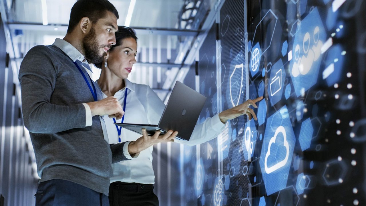 IT specialists holding a laptop and discussing work