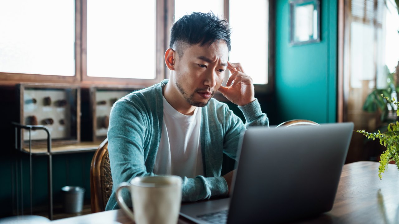 A stressed man using a laptop