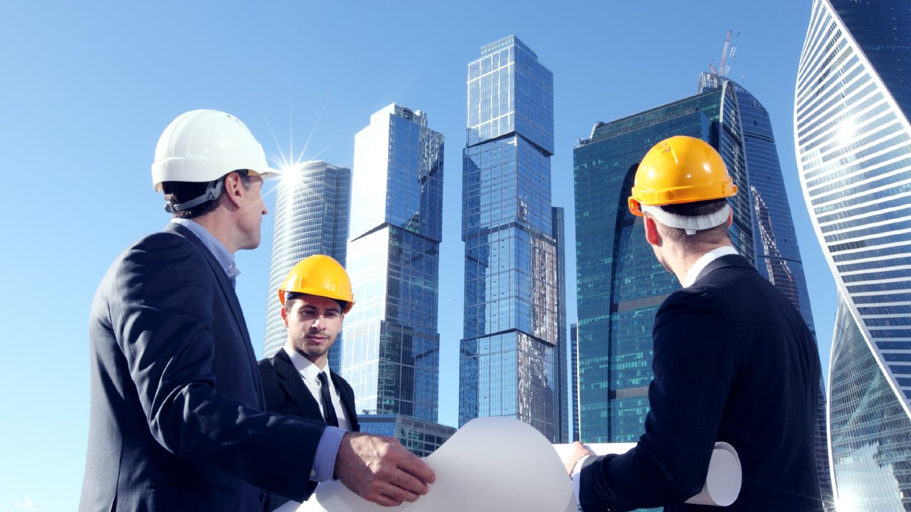 Property developers and engineers at construction site of a high rise building assessing risks for insurance