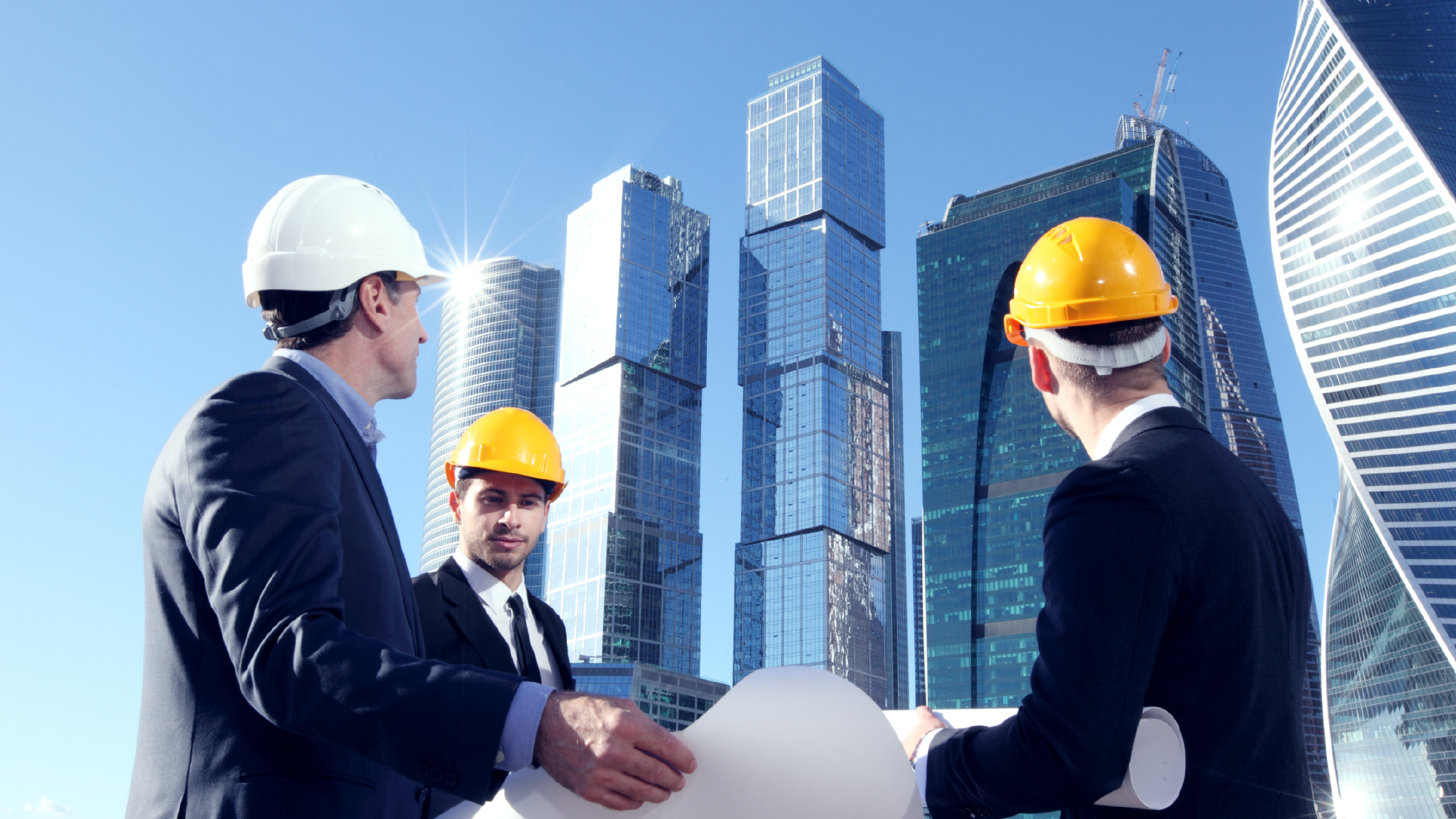 Property developers and engineers at construction site of a high rise building assessing risks for insurance