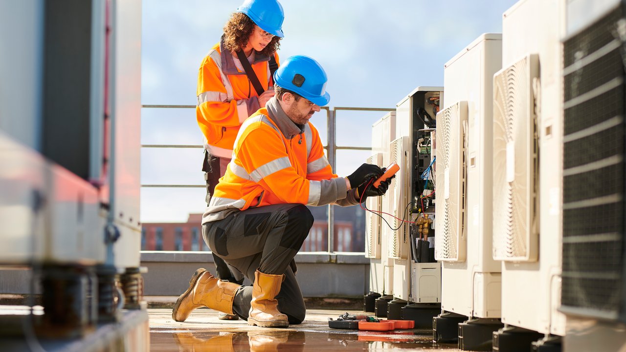 HVAC engineers and inspectors wearing safety gear and inspecting an air conditioner