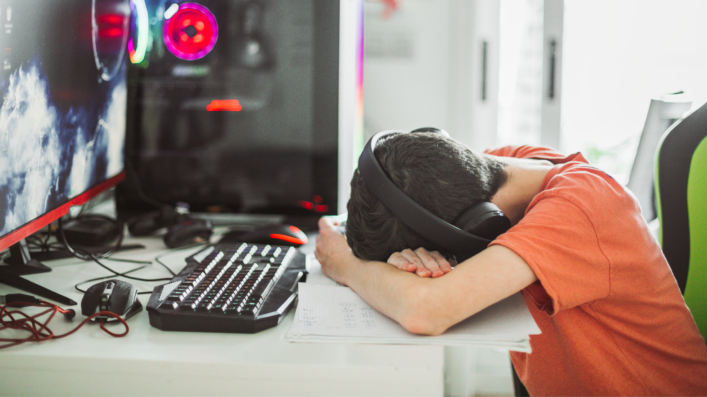 A cyberbullied student stressed and sitting at his desk with his head down in front of his computer