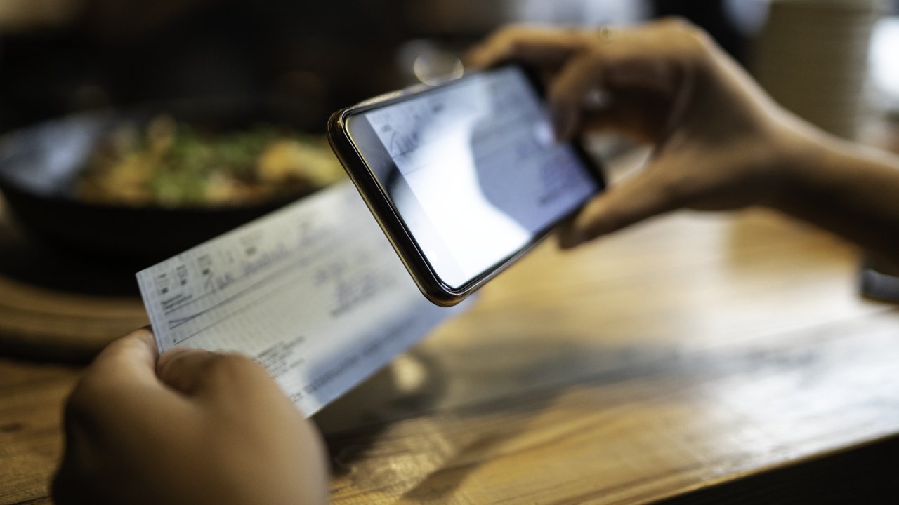 A person depositing an expense reimbursement cheque electronically using a mobile device