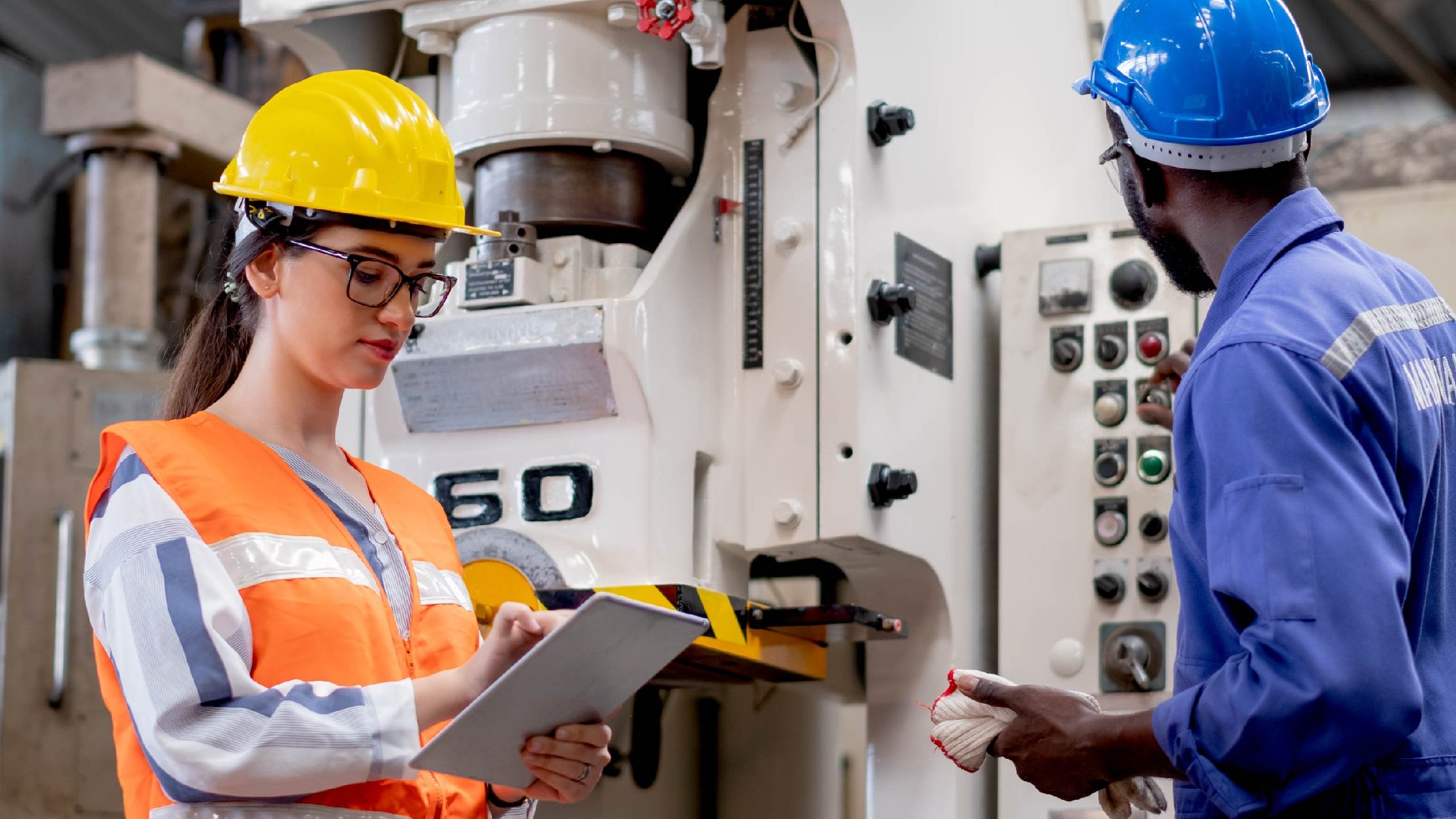 Jurisdictional inspection requirements A man and a woman inspecting equipment, wearing protective gear and using a tablet