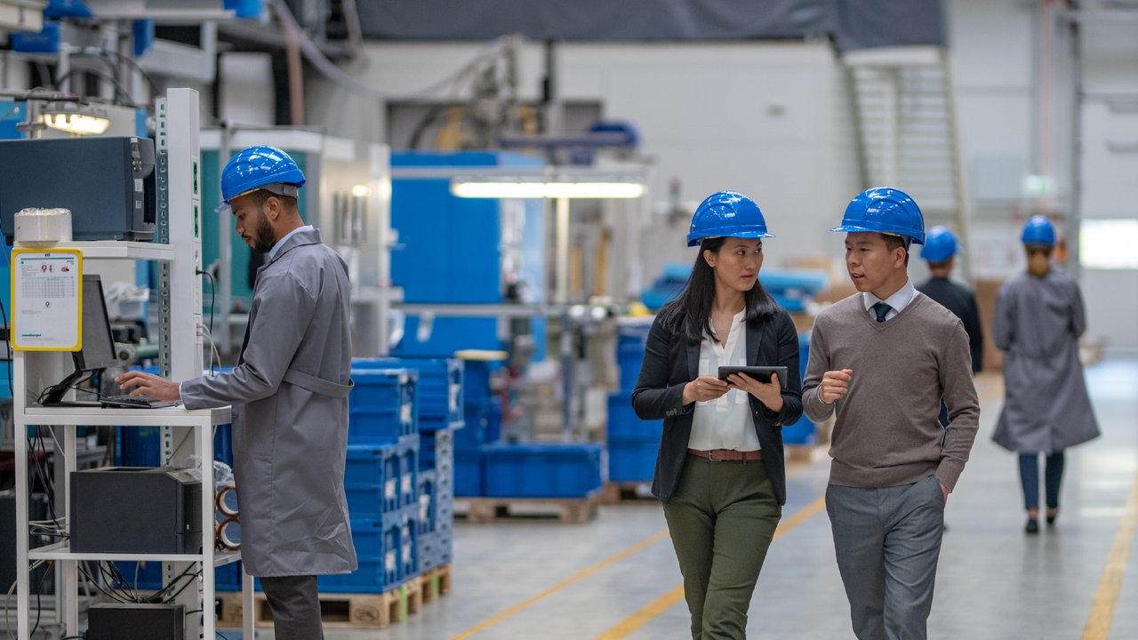 Une femme et un homme inspectant l'équipement dans une usine, utilisant une tablette électronique