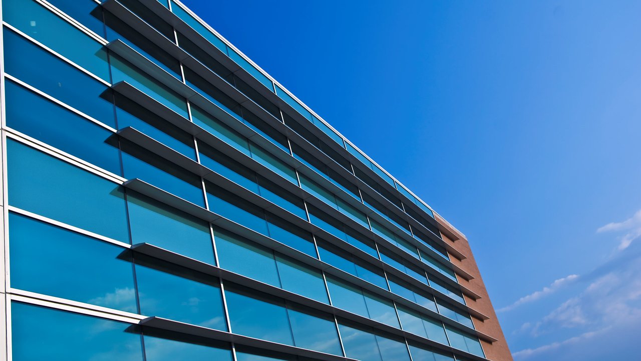 A modern building with large glass windows and horizontal overhangs against a clear blue sky.