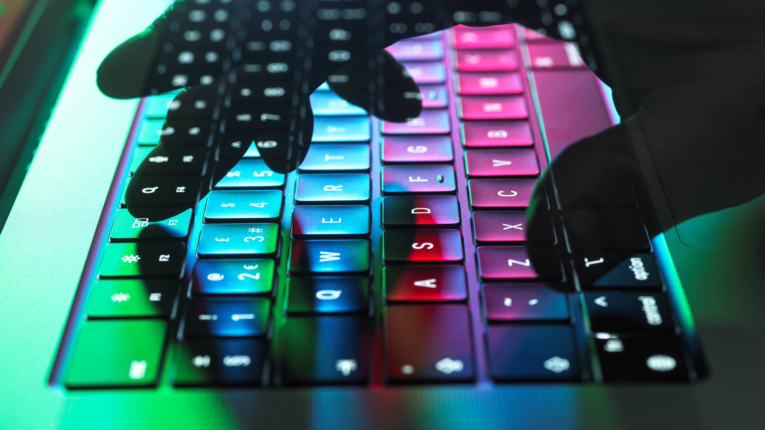 A person typing on a laptop, with multiple colours cast onto the machine