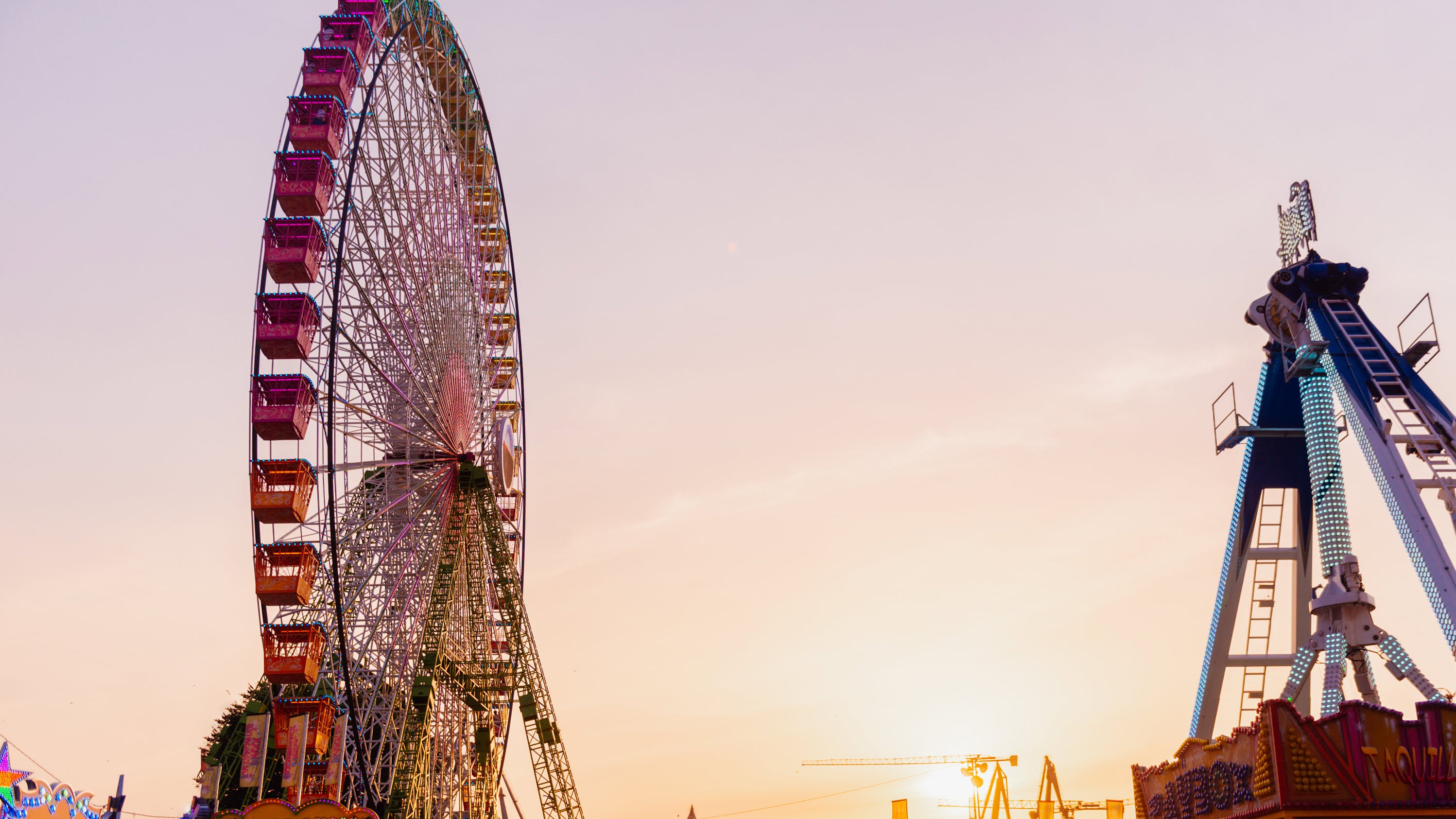 Amusement Parks: Engineering Inspection Services A colorful ferris wheel and amusement ride against a sunset sky.