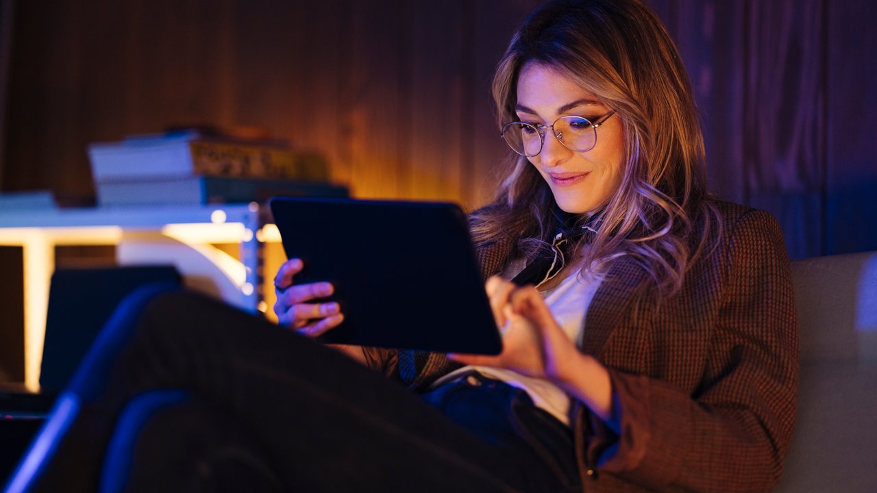 Middle-aged female using computer tablet at night