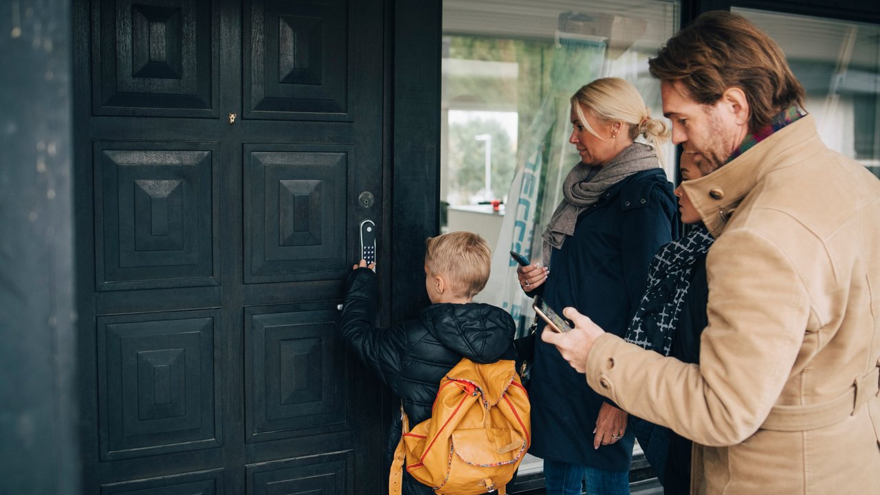 Family using smart lock at front door outside of home