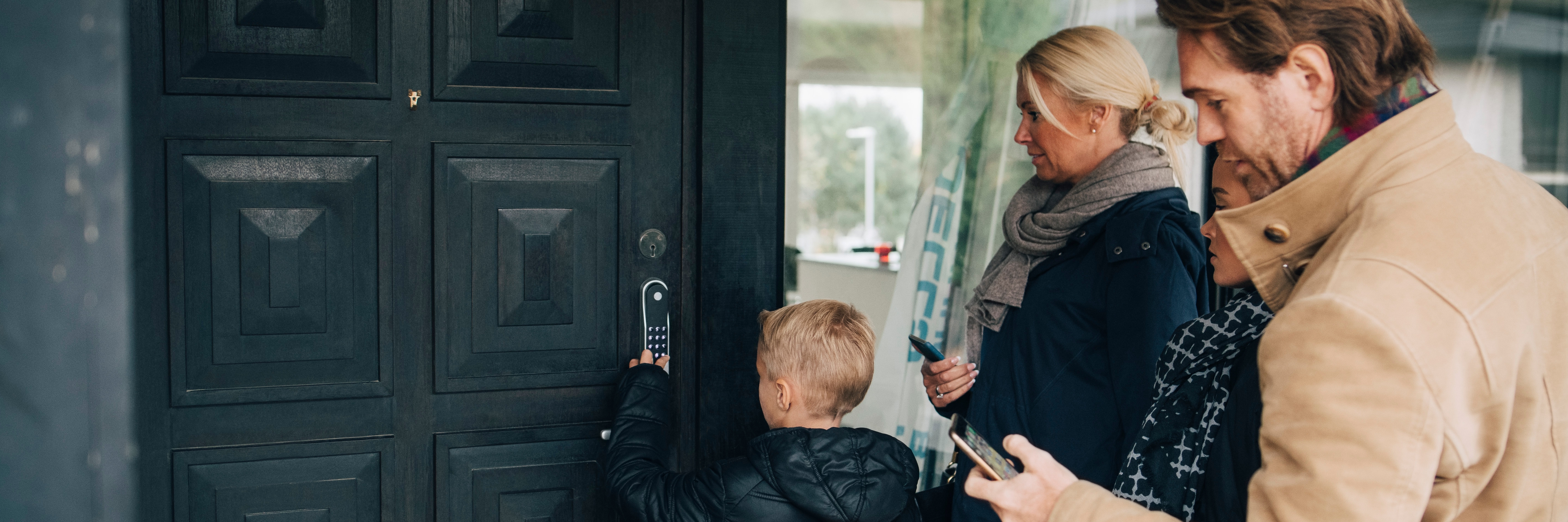Family using smart lock at front door outside of home