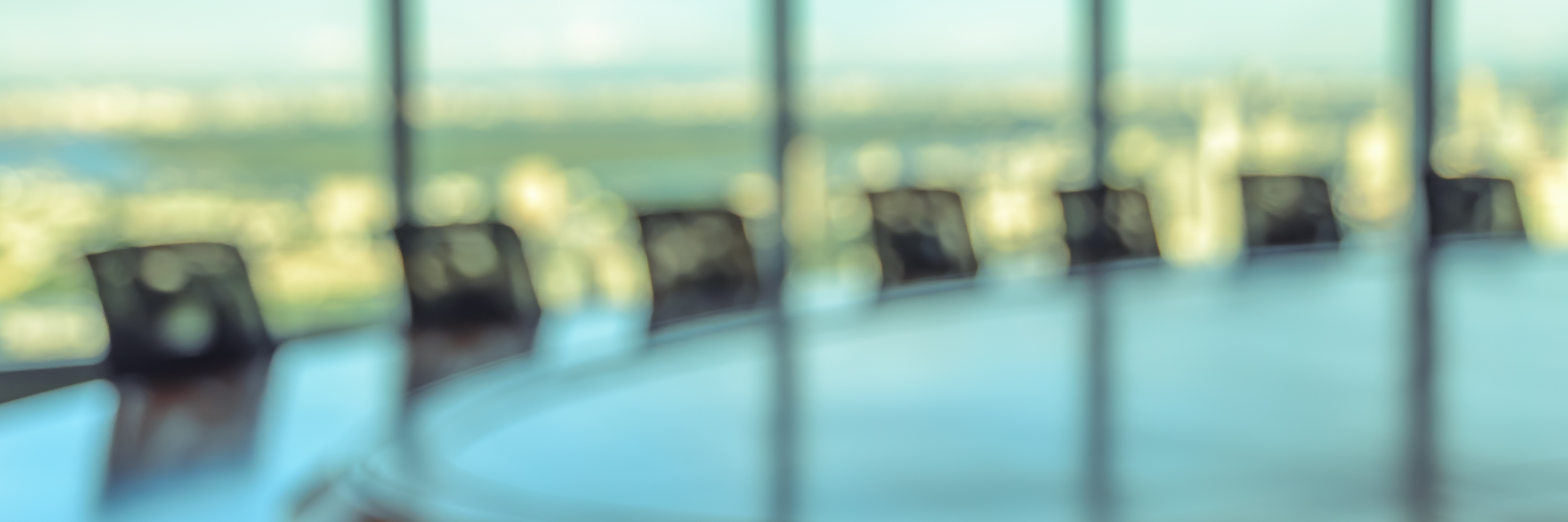Blurred image of empty boardroom with window cityscape background.