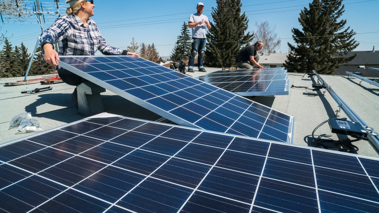 Workers installing solar panels on the roof of a residential building.