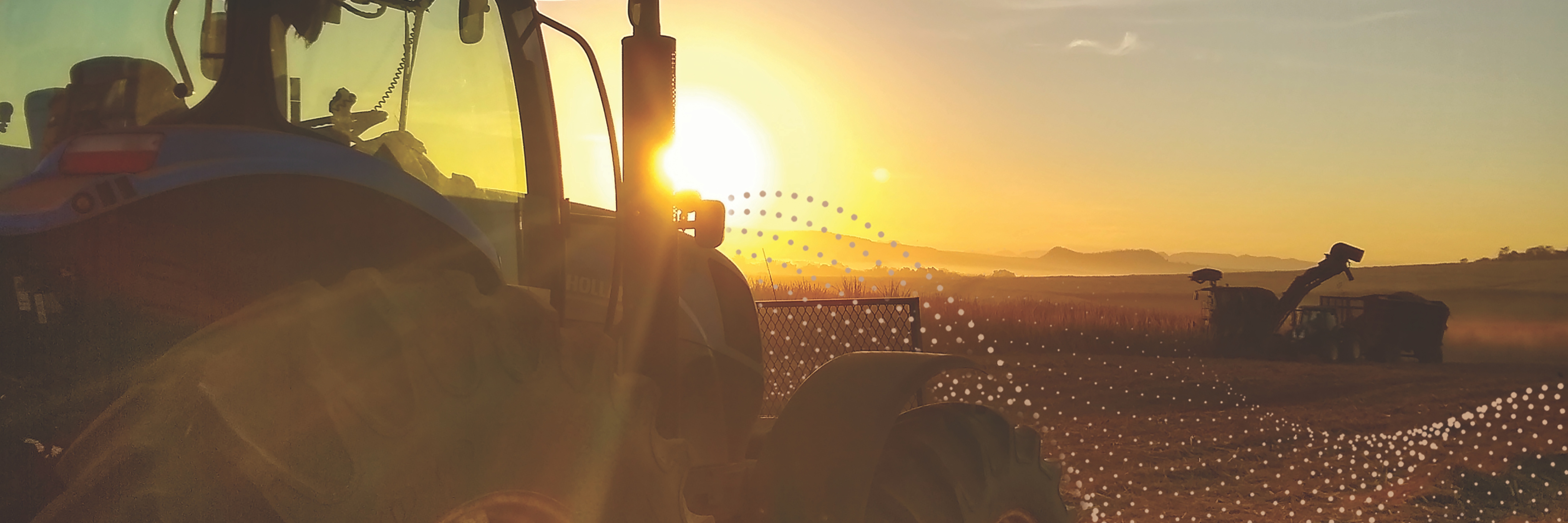 Farm equipment in field at sunset