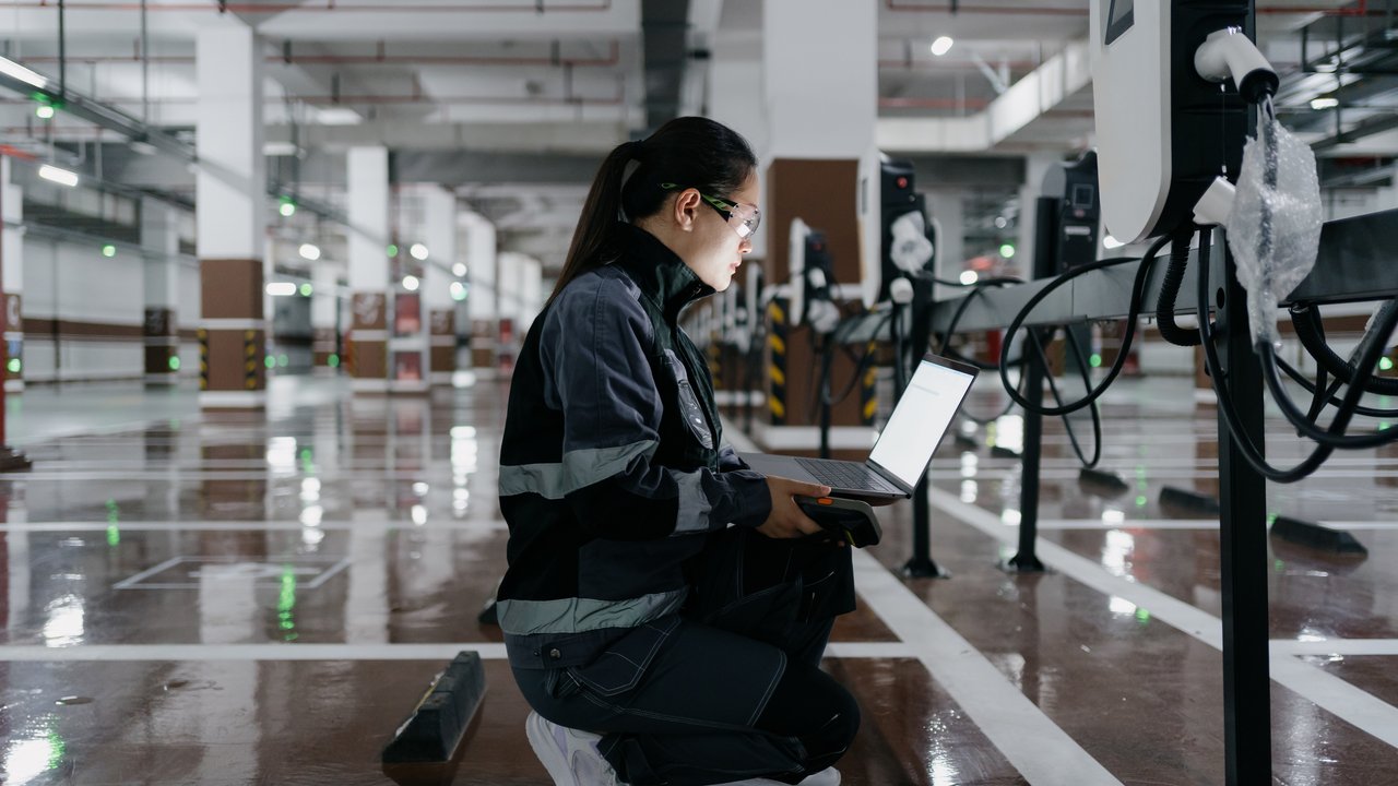Female engineer installing charging station in shopping mall parking lot