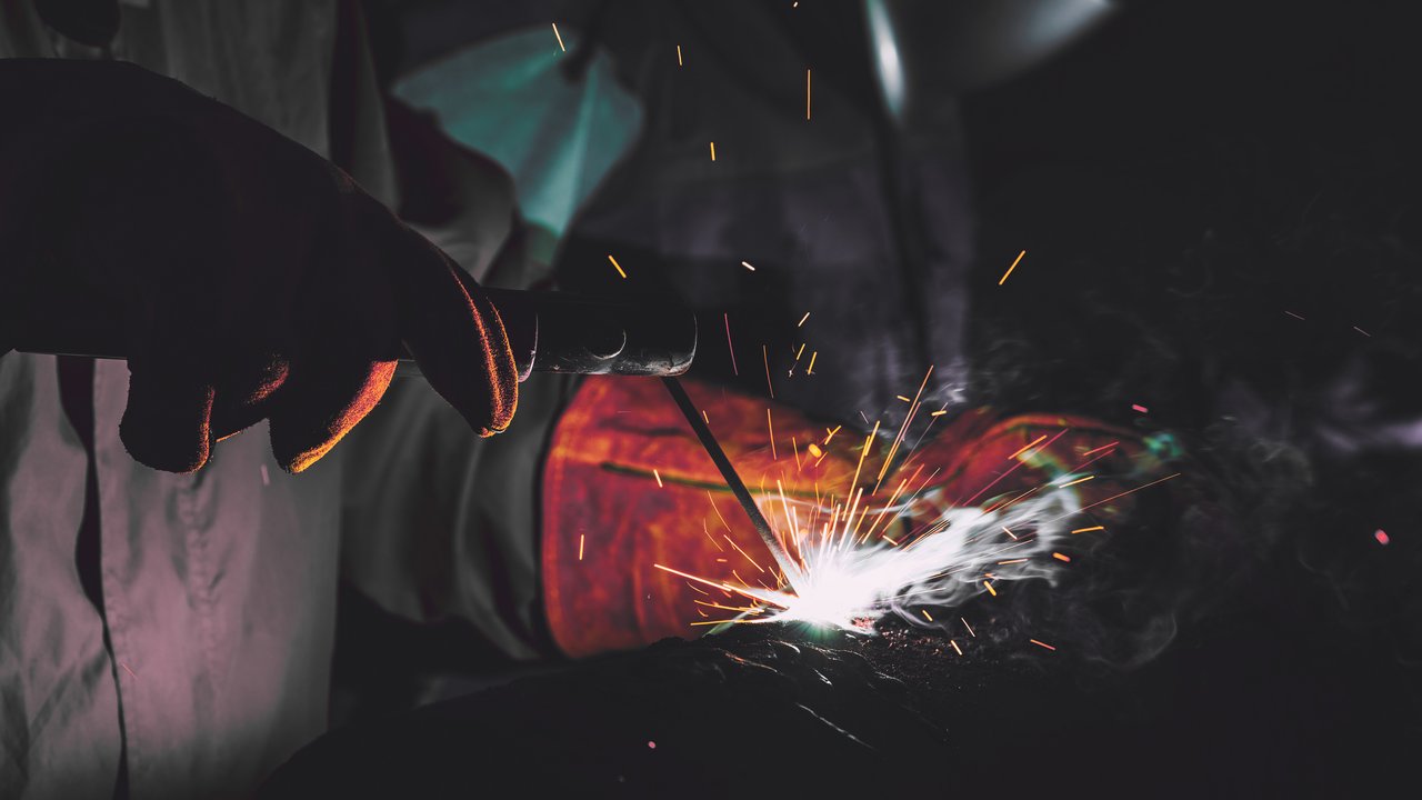 Close Up of industrial worker at the factory welding with protective mask.
