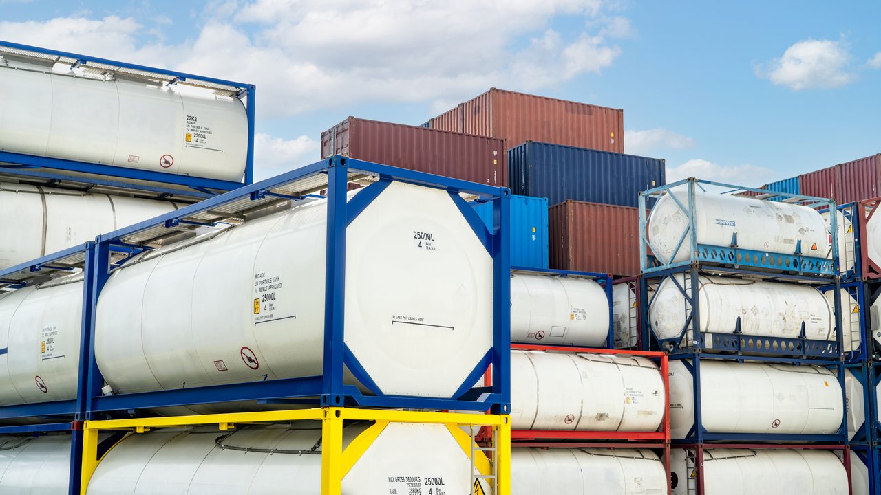 Chemical tank container. ISO tank container for chemical delivery. Bulk liquid transport. Chemical company. Container freight area. Global logistics business. Chemical container for truck transport.