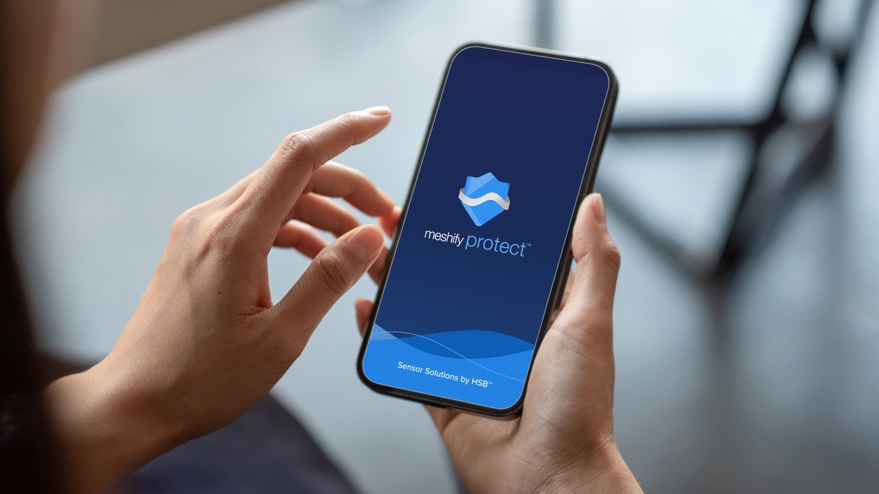 Close-up of a business person hand holding a smartphone with HSB Meshify Protect™ IoT Sensor App.