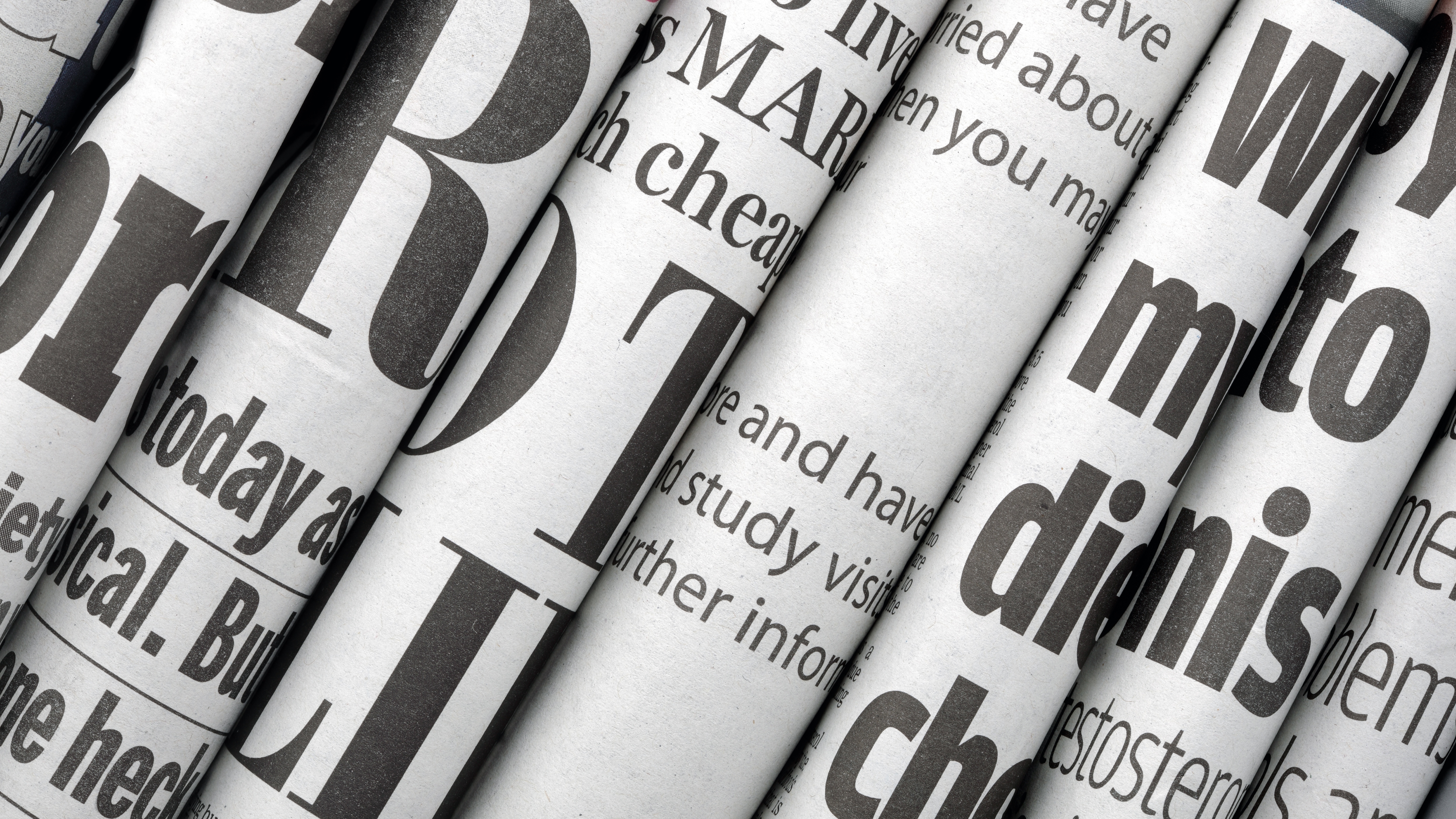Newspaper headlines shown side on in a stack of daily newspapers