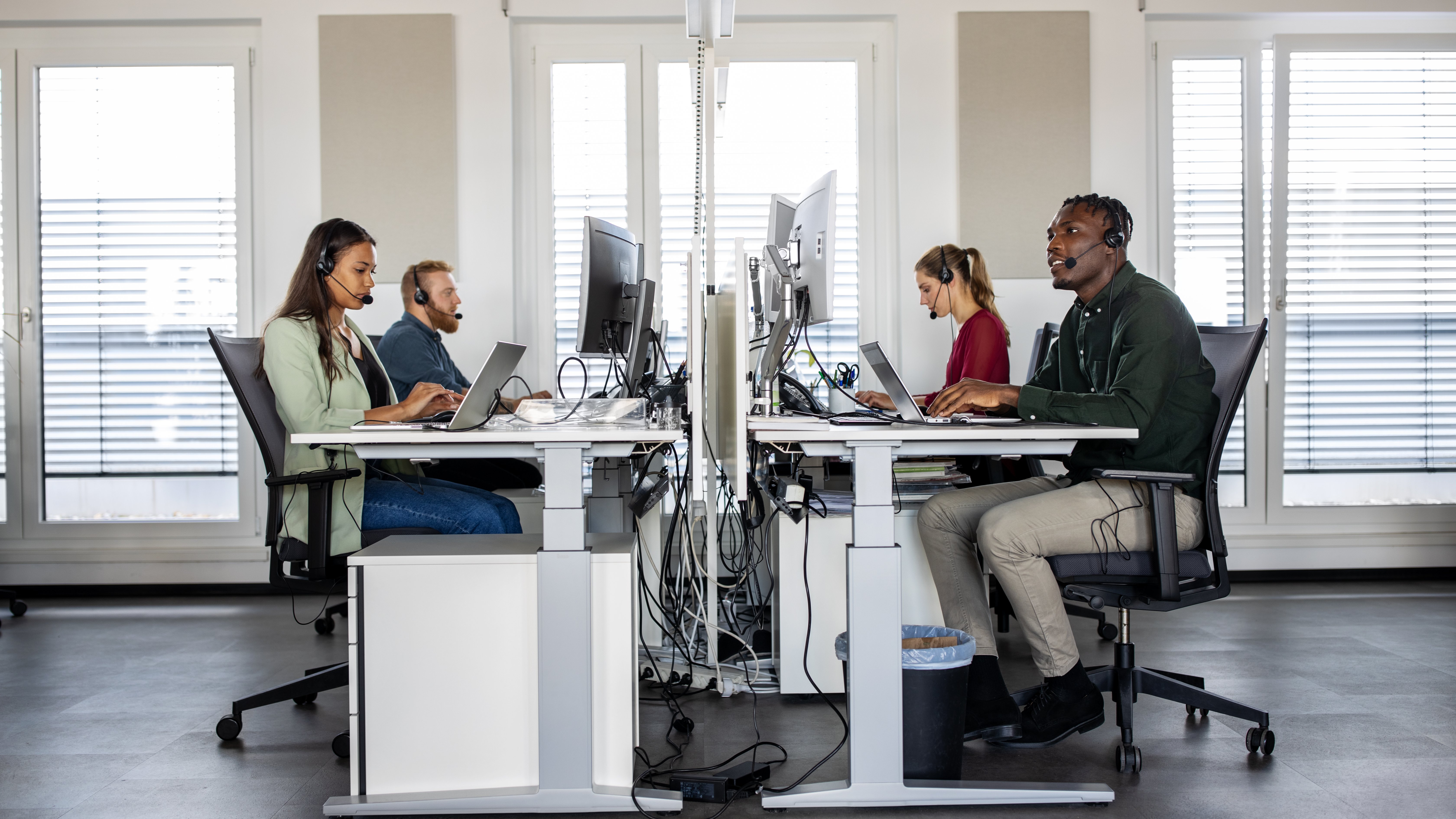 Claims Group of help desk operators wearing headsets and working at their computers in a call center.