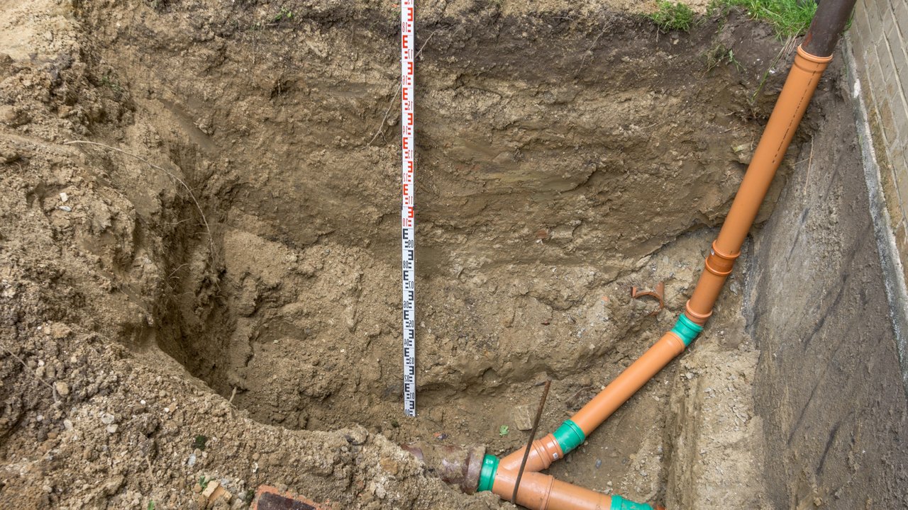 Laying a sewage pipe at the corner of a terraced house construction site.