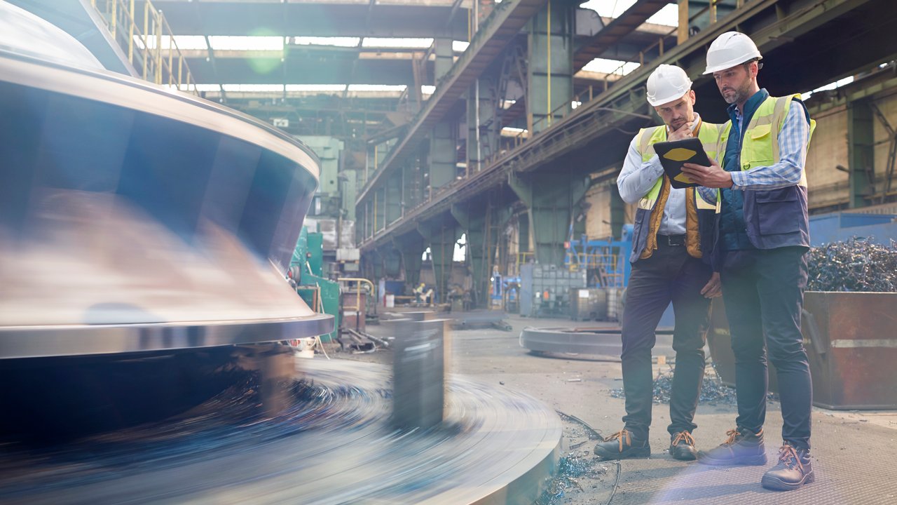 Male engineer working at glowing digital tablet in dark factory