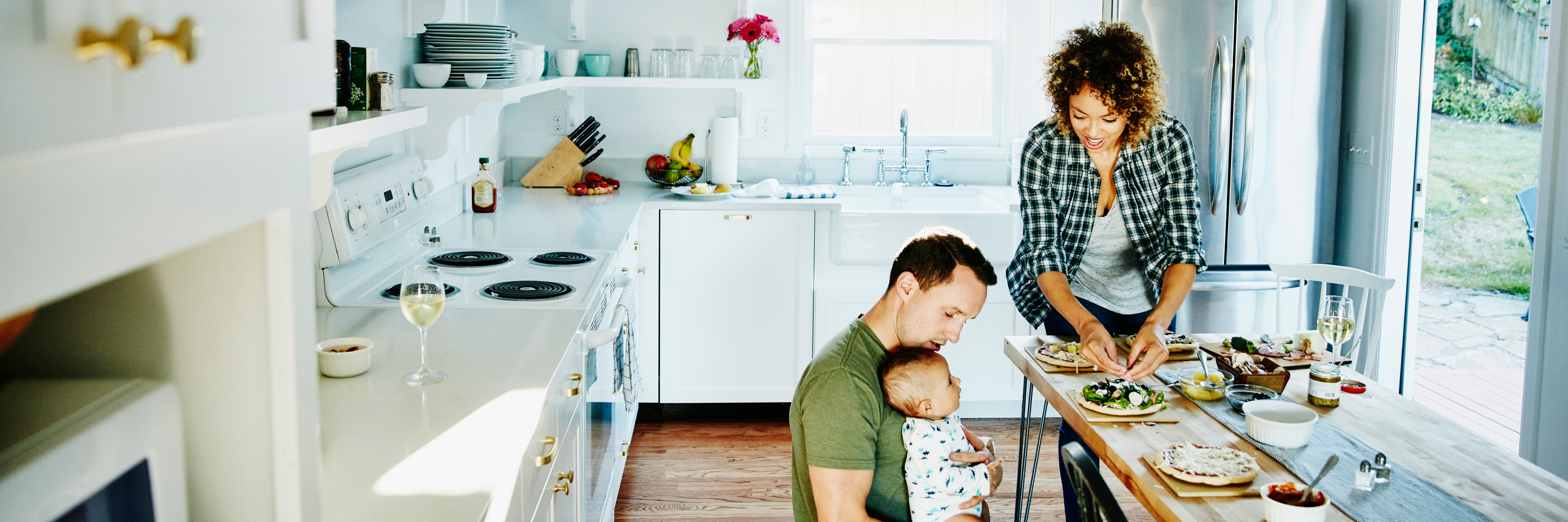 Father holding infant while preparing dinner.