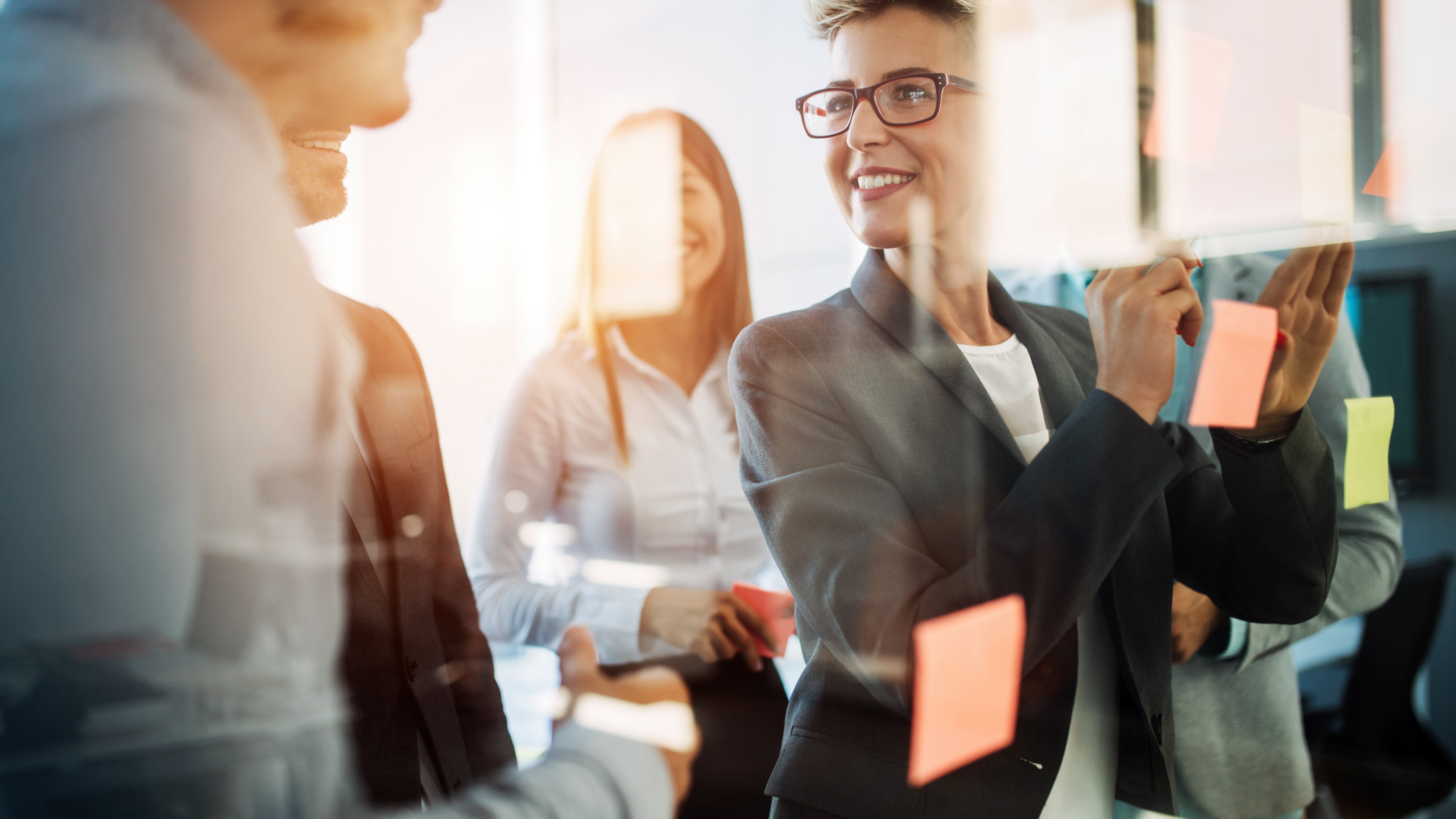 Strategic leadership starts with claims Business professionals in a strategy or brainstorming meeting writing on post it notes