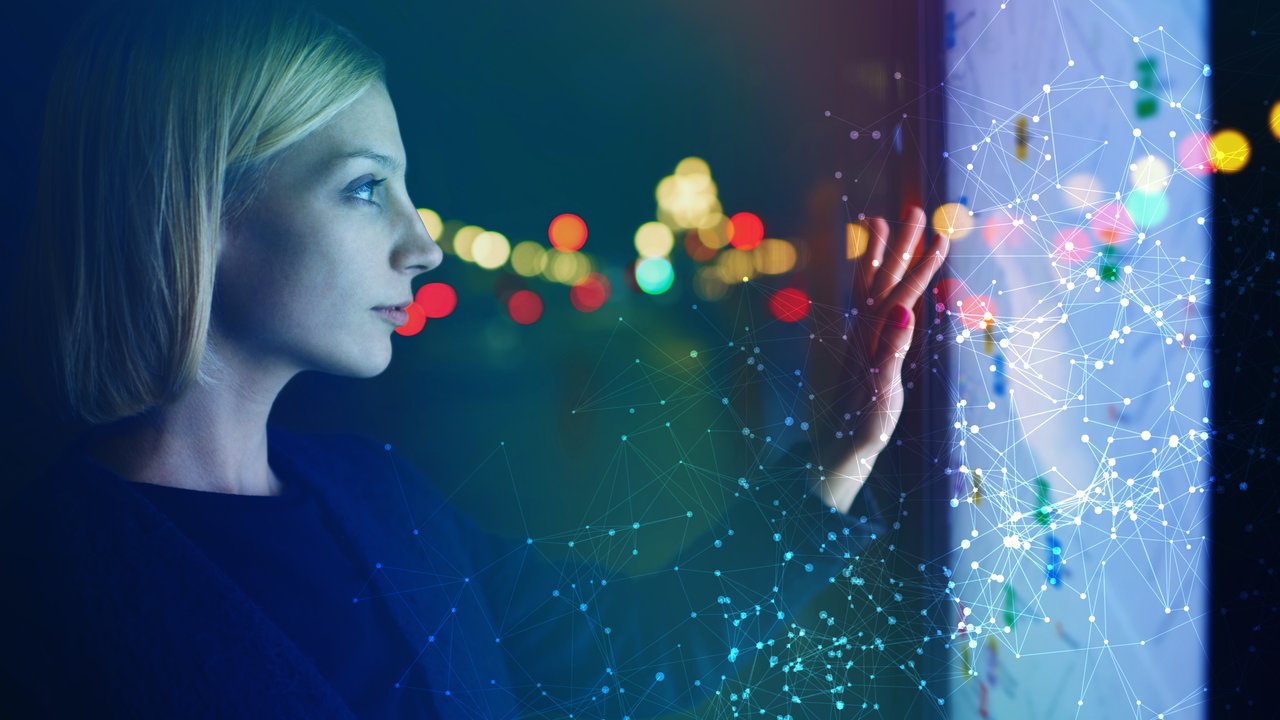 Young female tourist using smart city gadget to get direction in Barcelona central, female in night city standing front big digital screen with city map routes and locations shown on it,filtered image