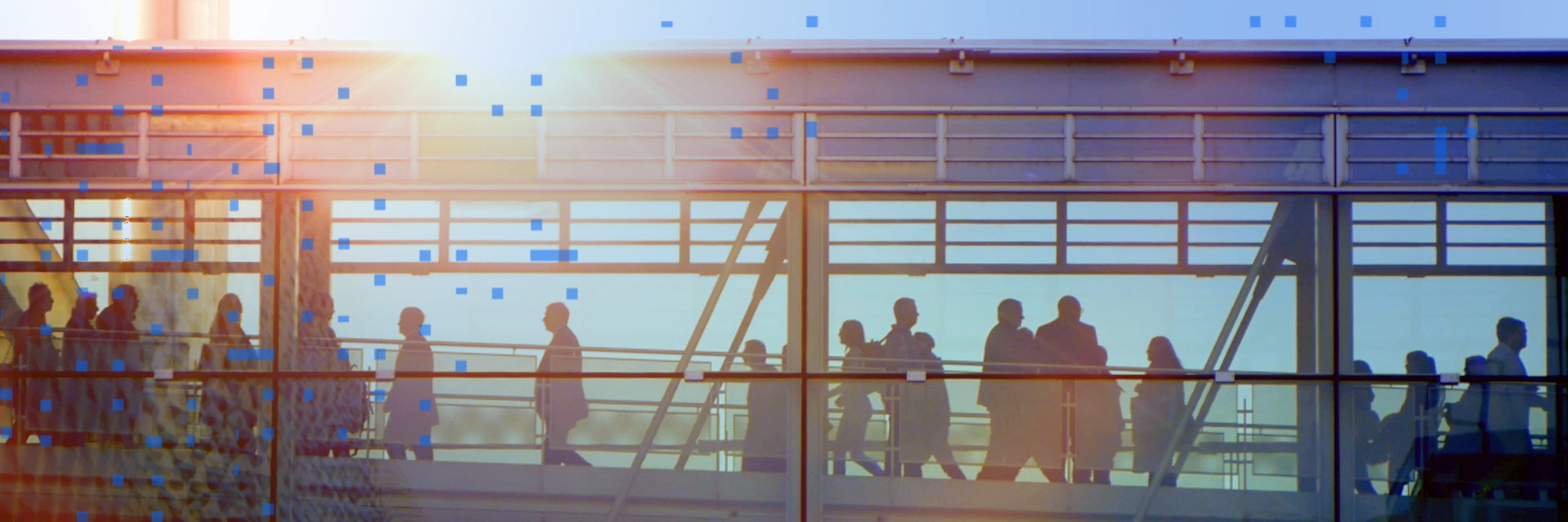 Business professionals  walking across an enclosed city glass bridge 