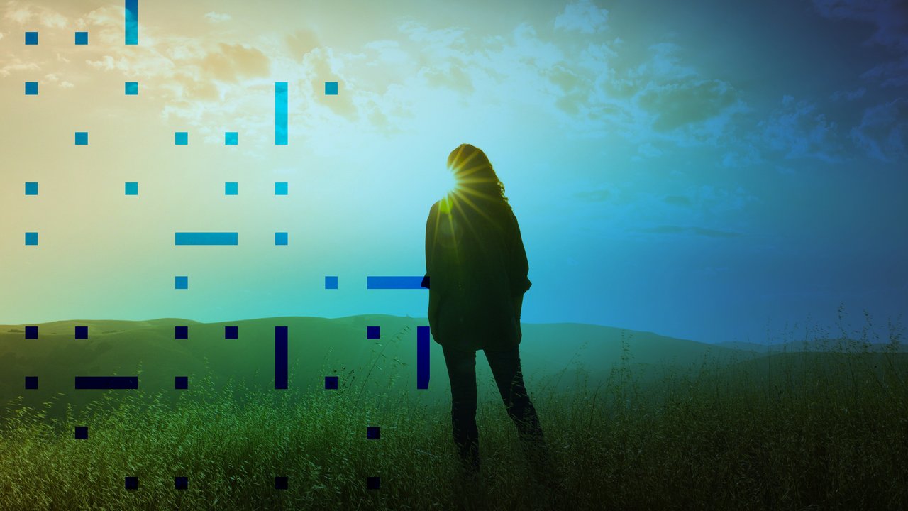 Silhouette of person standing on grass while facing sunlight