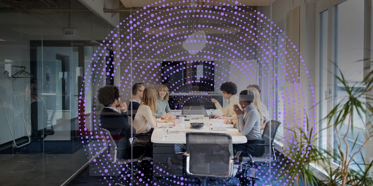Perspectives A diverse group of people in a meeting room around a table, with a digital overlay of purple dots.