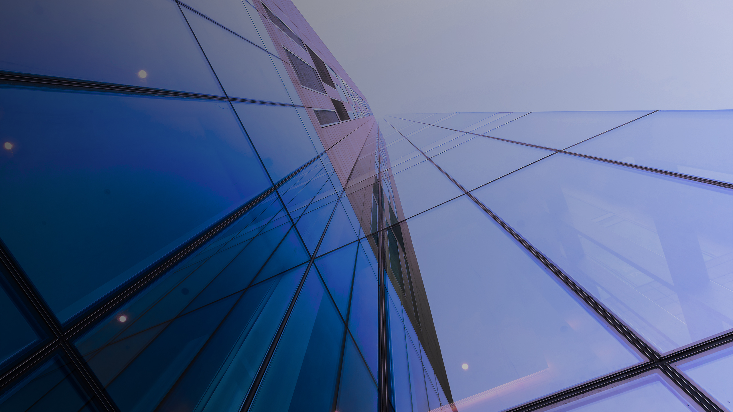 A close-up view of a modern glass building, reflecting light and showing geometric patterns.