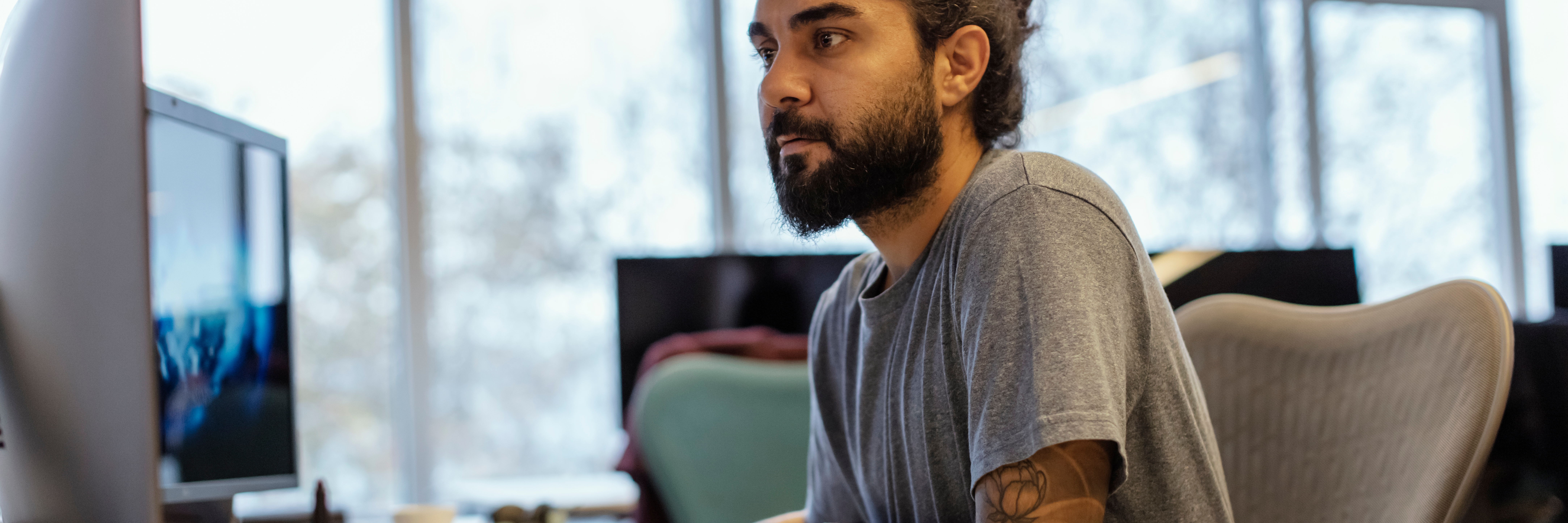 Portrait of Stylish Hipster Guy with Tattoo on Hand, Writes Notes in Computer at Office - stock photo