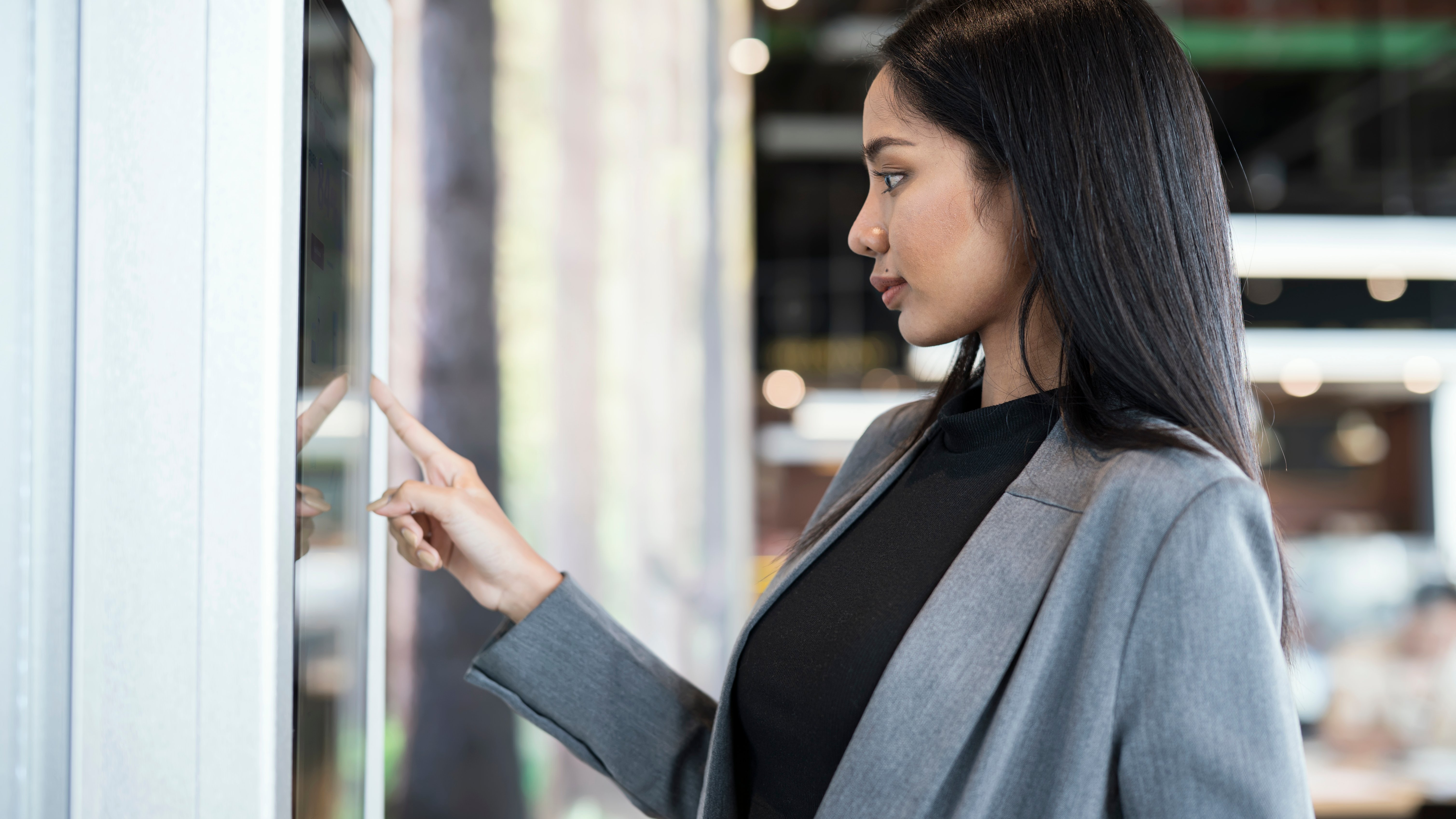 Innovative Framework for Self-service Kiosks Solution. Businesswomen using touch screen display to confirm order or payment of product, service at a kiosk machine.