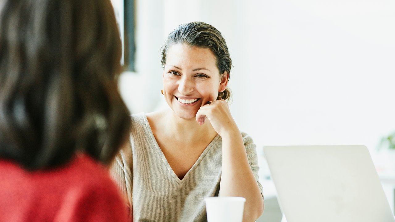 Smiling businesswoman in discussion with colleague during meeting in office conference room