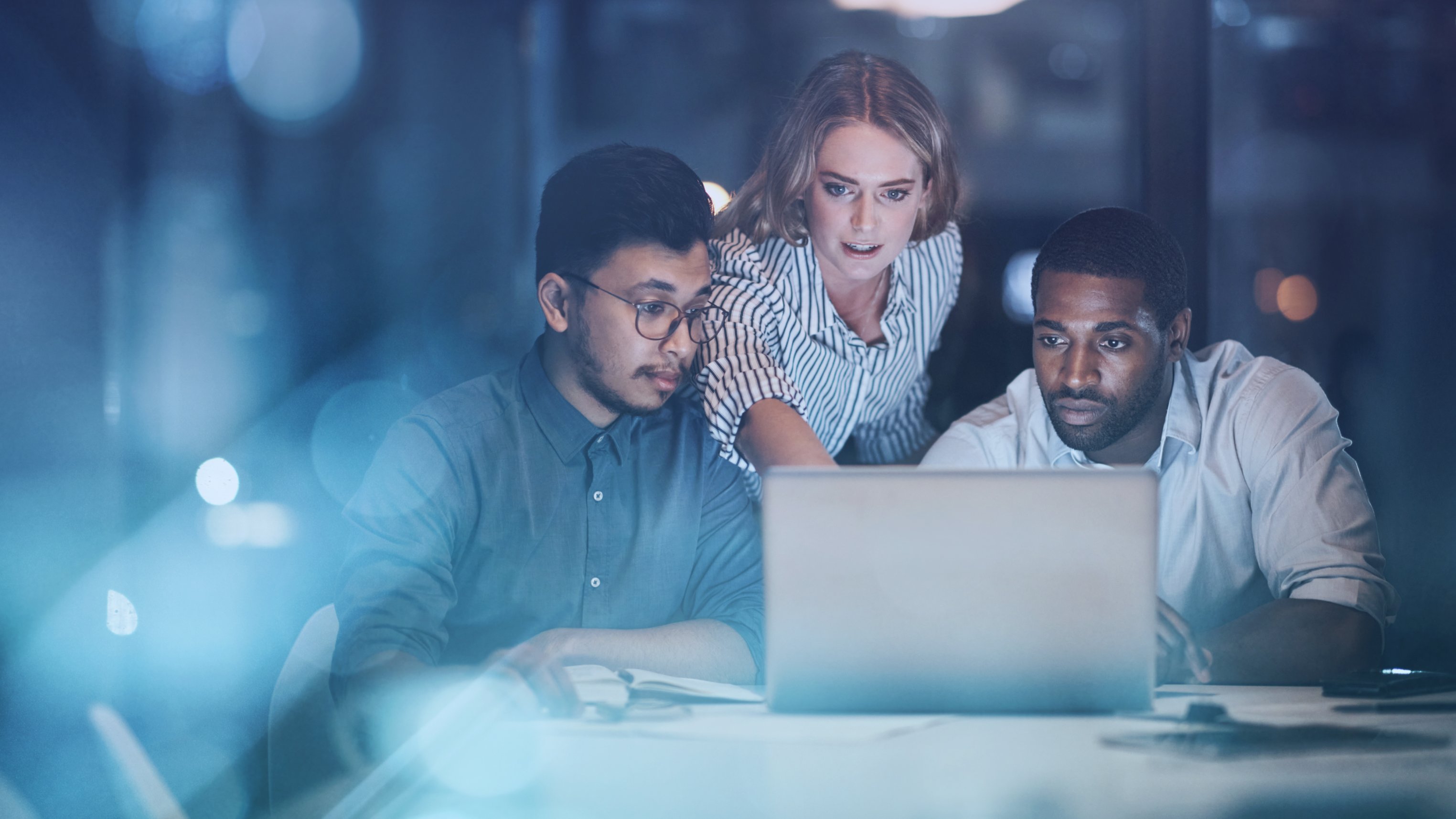 Cropped shot of three young businessmpeople working together on a laptop in their office late at night