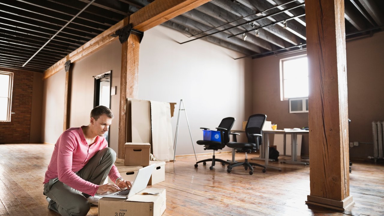 Entrepreneur using laptop in empty creative office space
