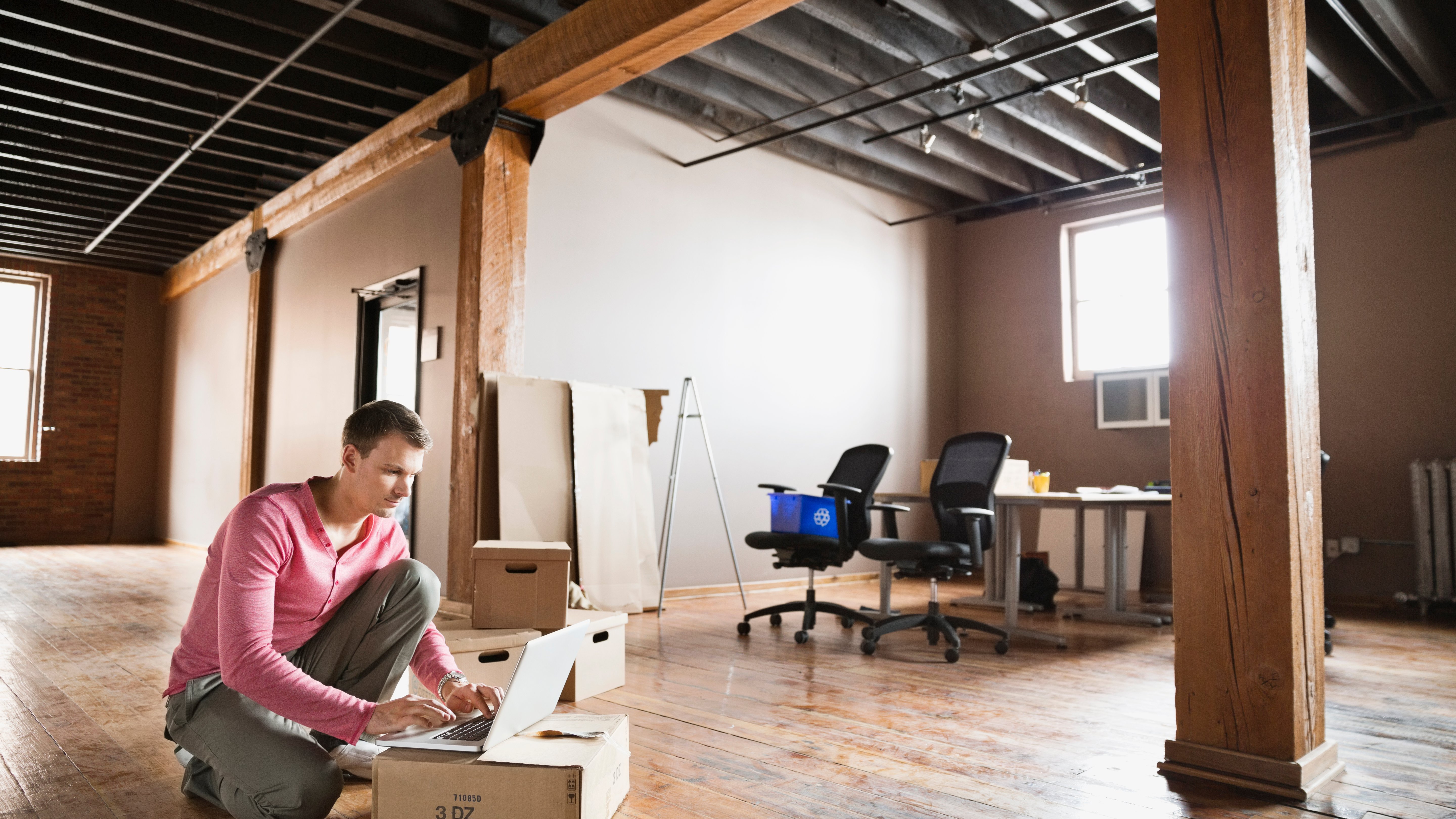 Entrepreneur using laptop in empty creative office space