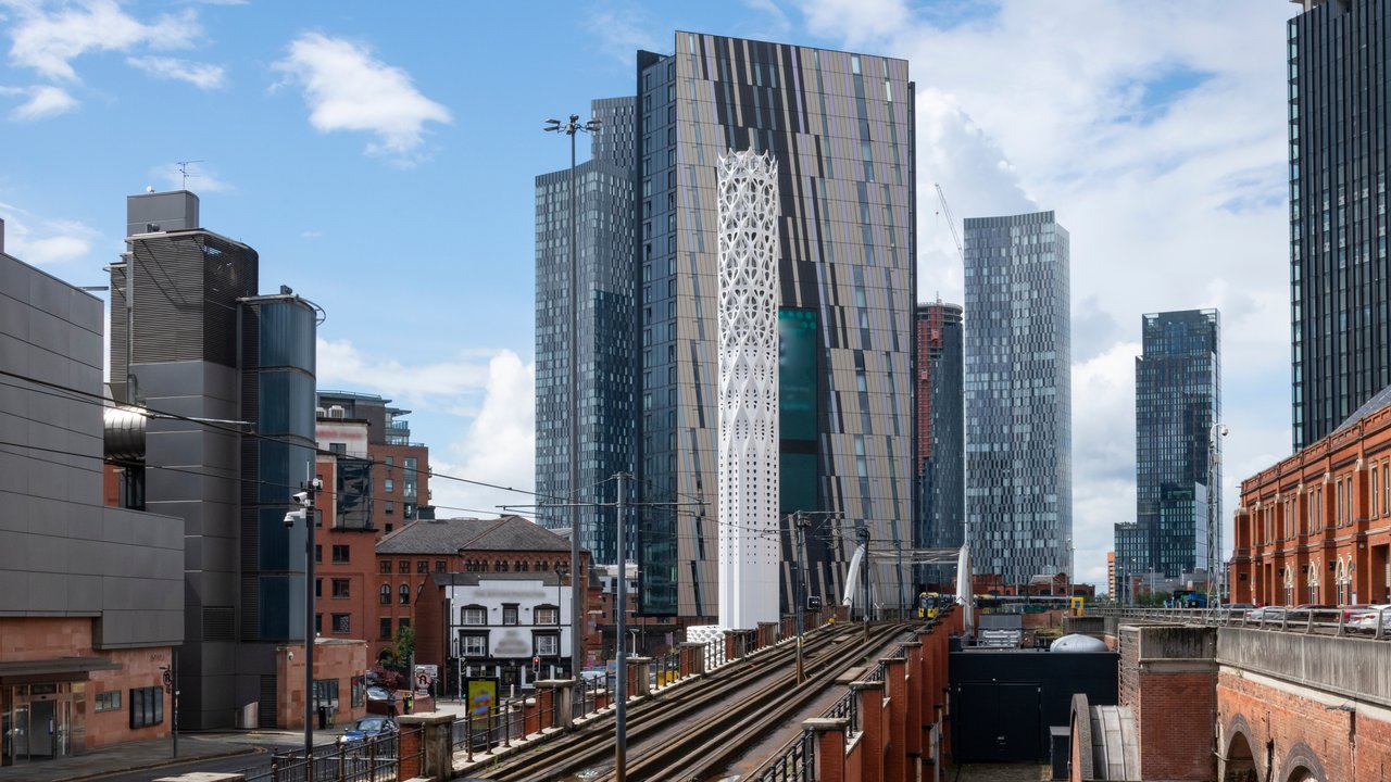 Cityscape featuring modern skyscrapers, railway tracks, and a mix of architectural styles under a blue sky.