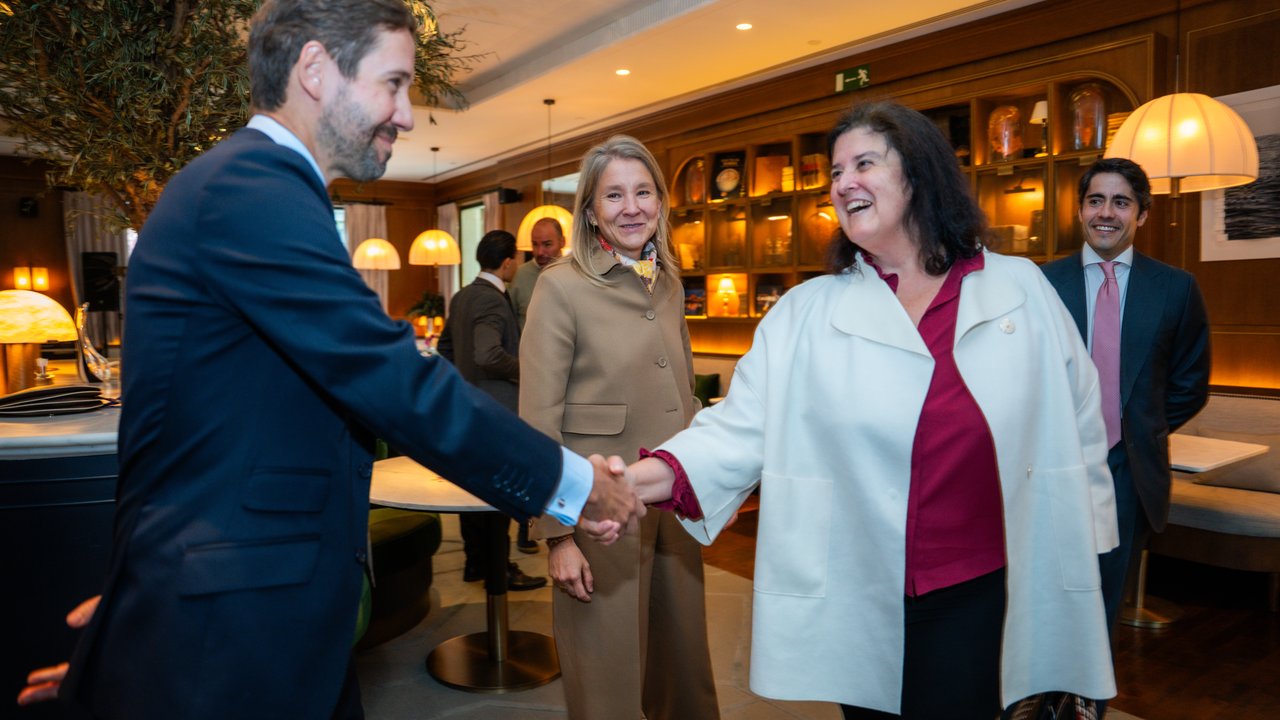 A man shakes hands with a woman in a restaurant, with two other people in the background and decorative lighting.