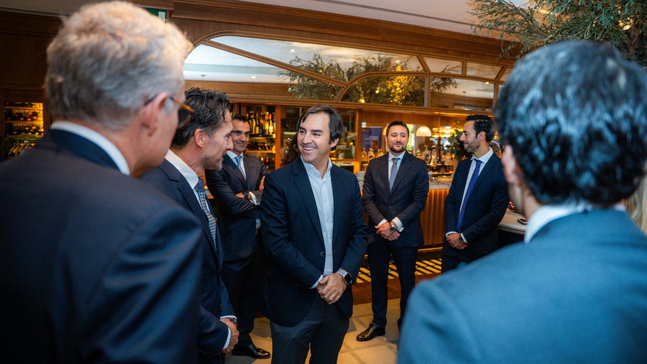 A group of men in suits engaged in conversation in a well-lit bar setting.