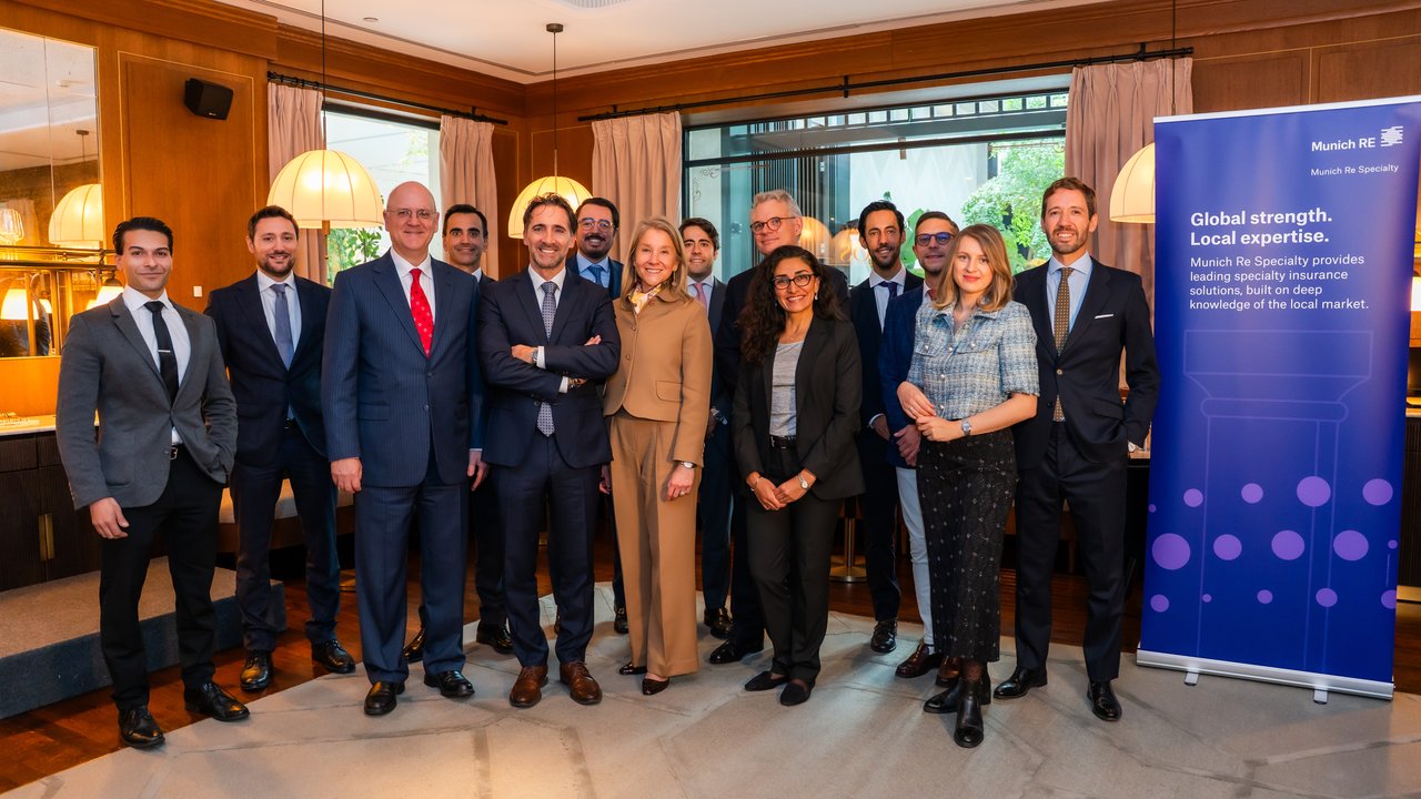 A group of professionals in business attire poses in a well-lit indoor setting with a banner in the background.
