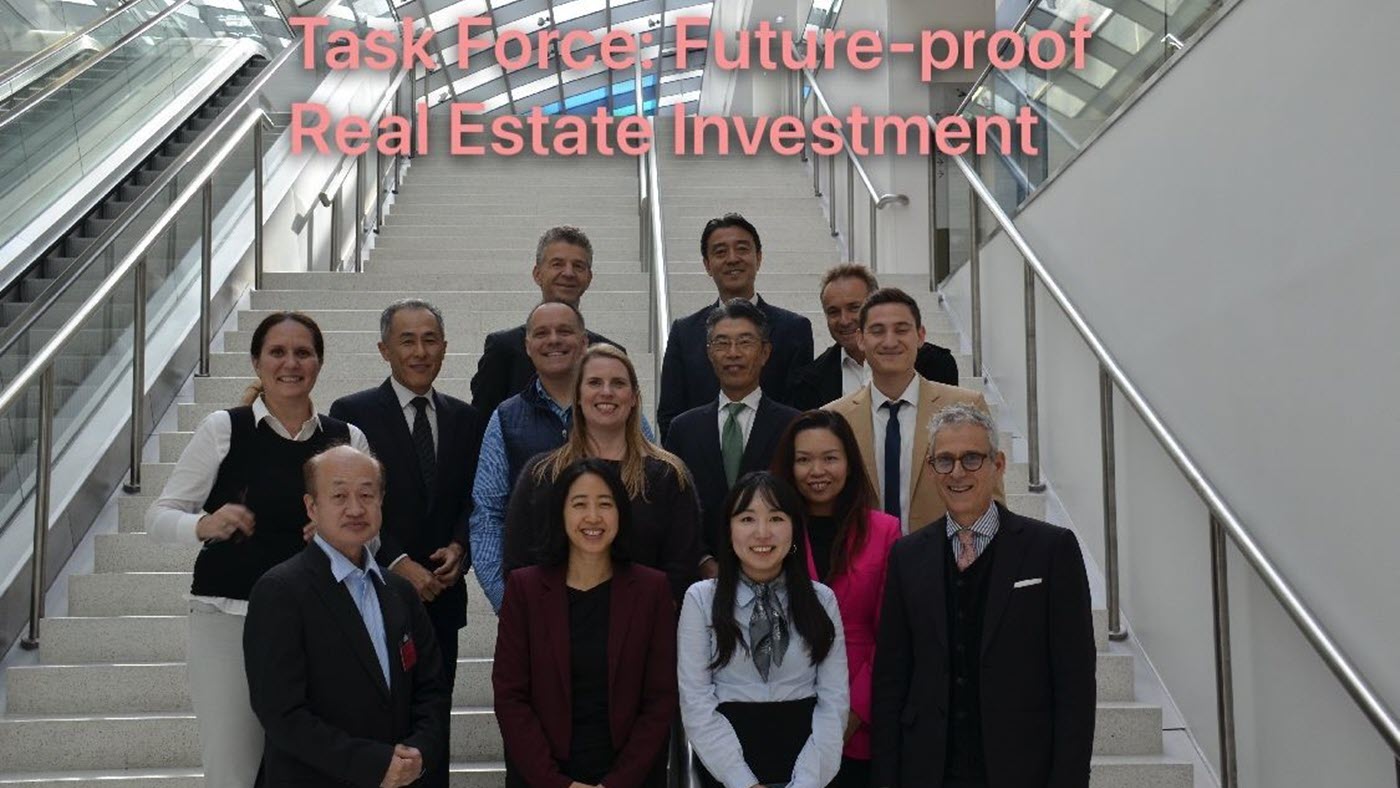 A group of people in formal attire poses on a staircase, with a glass ceiling above and a text overlay.